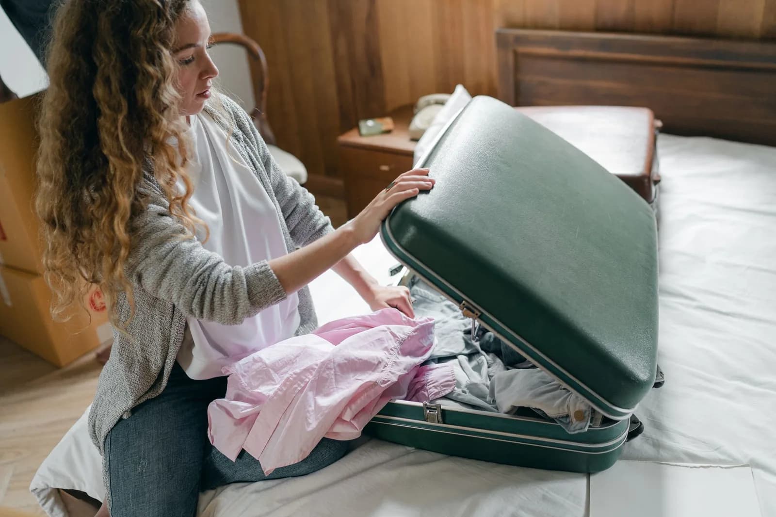 Una viajera prepara una maleta abierta sobre la cama