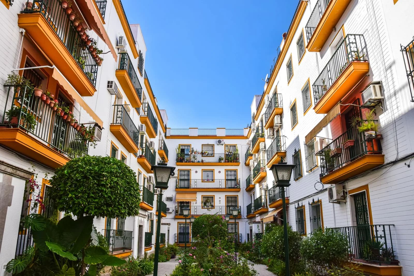Patio residencial andaluz rodeado de fachadas blancas y balcones