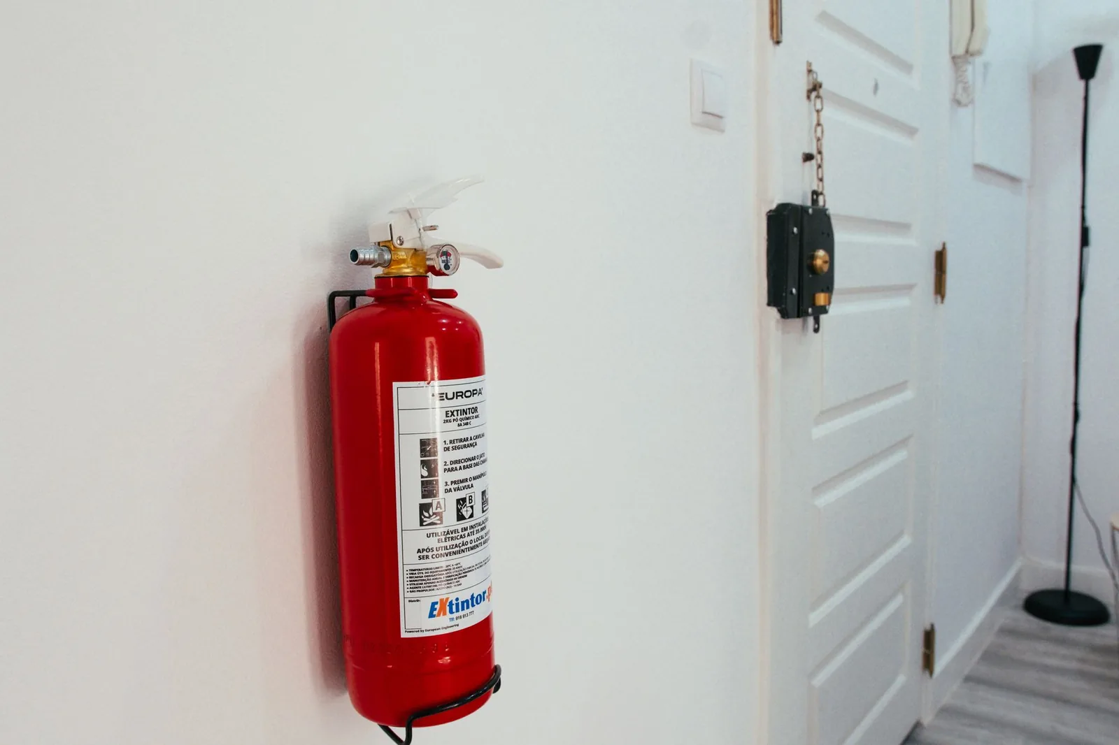 Extintor rojo instalado junto a la puerta de un alojamiento