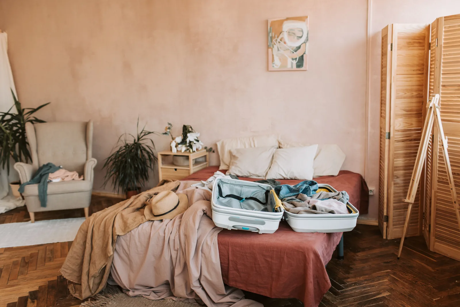 Maleta abierta con ropa sobre una cama en una habitación luminosa.