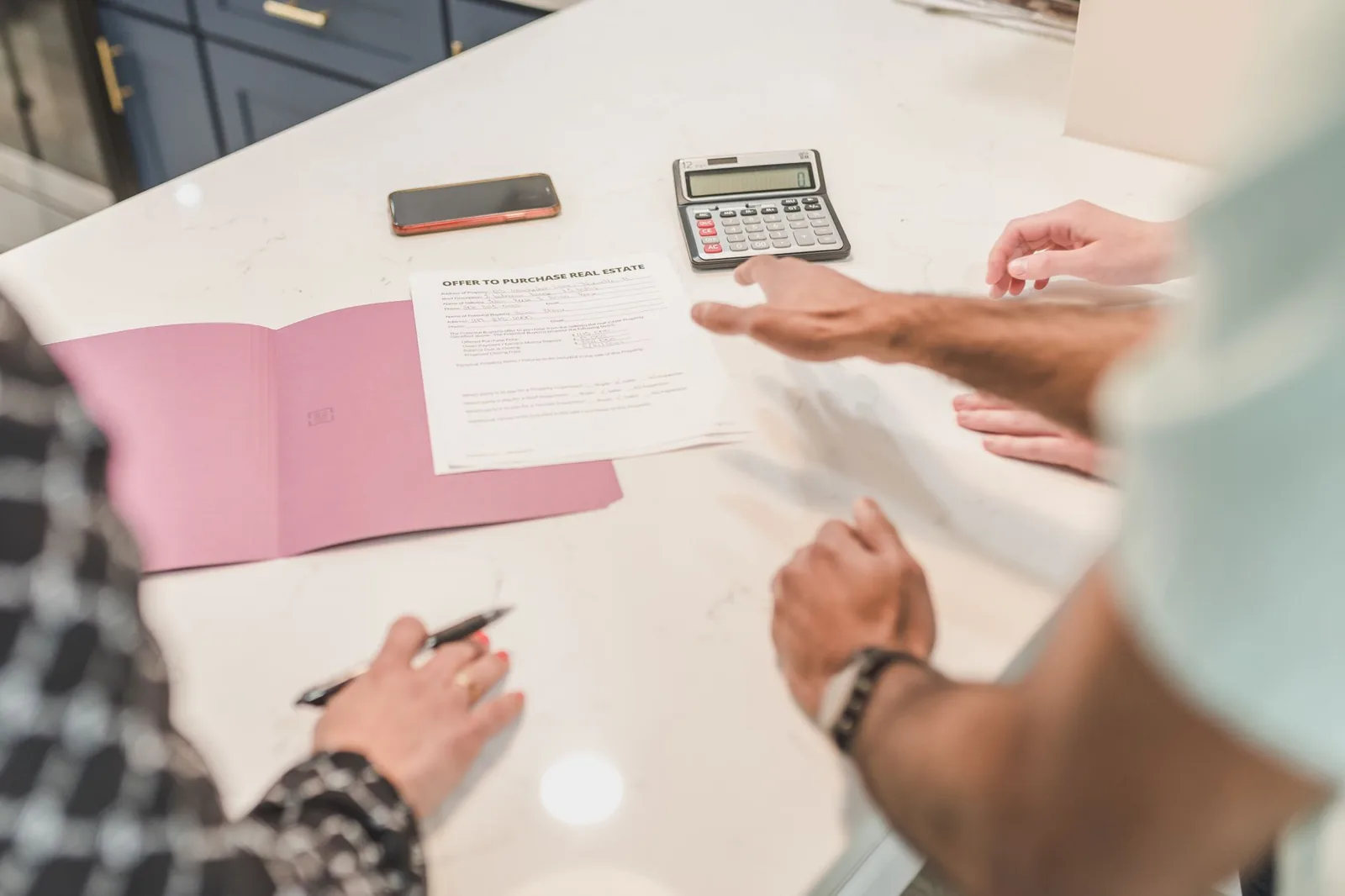 Varias personas revisan documentación inmobiliaria junto a una calculadora