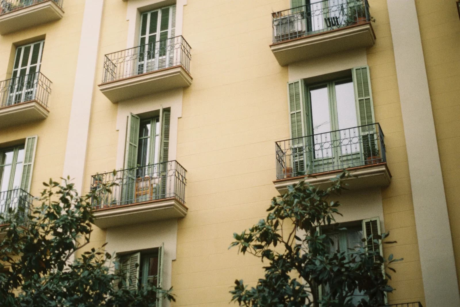 Fachada de un edificio con balcones y contraventanas verdes